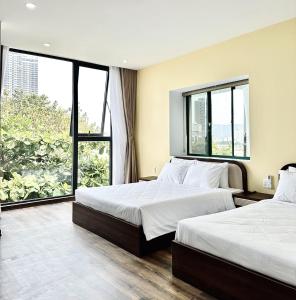 two beds in a hotel room with large windows at Han Riverine Hotel & Cafeteria DaNang in Danang