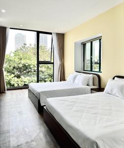 two beds in a hotel room with a large window at Han Riverine Hotel & Cafeteria DaNang in Danang