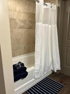 a bathroom with a shower with a white shower curtain at Elite Retreat in Addison Circle in Addison
