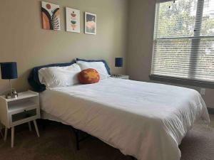 um quarto com uma cama branca e uma almofada em Elite Retreat in Addison Circle em Addison