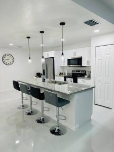 een witte keuken met een aanrecht en stoelen en een klok bij White house 1 in Lehigh Acres