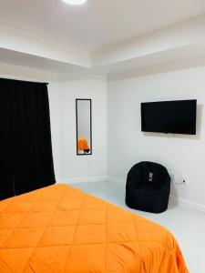 een slaapkamer met een oranje bed en een flatscreen-tv bij White house 1 in Lehigh Acres
