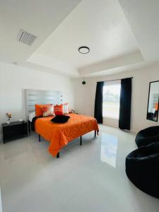 a bedroom with a bed with an orange blanket at White house 1 in Lehigh Acres