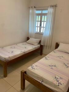 two beds in a room with a window at Residencial Sauaçhuy in Ipioca