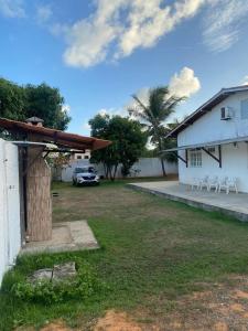 a yard with white chairs and a building at Residencial Sauaçhuy in Ipioca