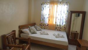a bedroom with a bed with a window and a chair at CG'S TRAVELLERS INN in Panglao