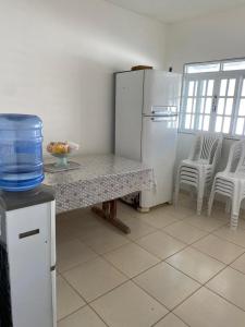 a kitchen with a table and a refrigerator and chairs at Residencial Sauaçhuy in Ipioca