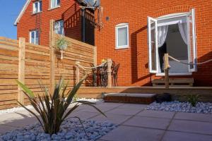 a house with a wooden fence and a patio at The Seashells Whitstable in Kent