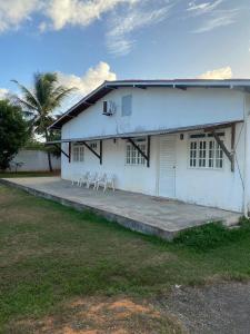 a white house with white chairs on a porch at Residencial Sauaçhuy in Ipioca