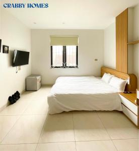 Schlafzimmer mit einem weißen Bett und einem TV in der Unterkunft Crabby homes in Hanoi