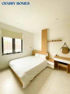 a bedroom with a large white bed and a desk at Crabby homes in Hanoi