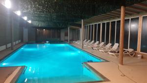 a large swimming pool with lounge chairs in a building at Complex Dalex in Drăgăşani