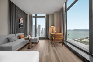 a living room with a couch and a large window at Shenzhen Shekou Prince Bay Yifei Hotel in Shenzhen