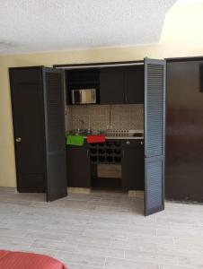 a small kitchen with black cabinets and a stove at Departamento con hermosa vista al mar y acceso a playa, 2 albercas in Acapulco