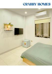 a white bedroom with a bed and a window at Crabby homes in Hanoi
