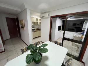 a kitchen with a white table and a potted plant at Apto 2D Capão da Canoa/Praça Flávio 150m Mar in Capão da Canoa +8 photos