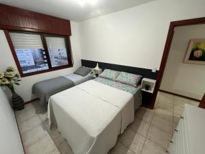a bedroom with two beds and a window at Apto 2D Capão da Canoa/Praça Flávio 150m Mar in Capão da Canoa