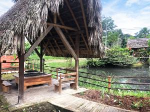 una cabaña con un banco, una mesa y agua en Coatí Lodge Misahuallí - FamiliyJungleParadise, en Puerto Misahuallí