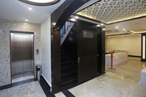 a hallway with a black door and a staircase at Collection O Hotel Pearl Blue in Tājganj