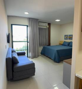 een slaapkamer met een bed, een bank en een raam bij Loft em frente à Praia in Vitória