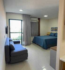 a bedroom with a bed and a couch and a window at Flat em frente à Praia in Vitória