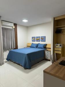 een slaapkamer met een blauw bed en een bureau bij Loft em frente à Praia in Vitória