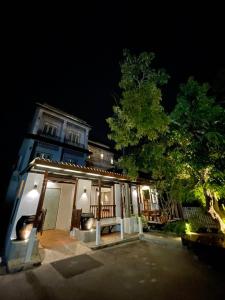 a house at night with a tree and a building at Thanicha Resort Amphawa in Amphawa