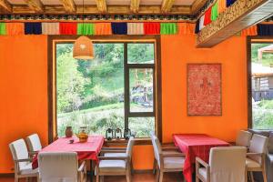a dining room with orange walls and tables and chairs at 九寨沟阿布氇孜民宿Jiuzhaigou Valley Abluzi B&B in Jiuzhaigou
