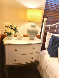 a white dresser with a lamp and flowers on it at Tyalgum Bed & Breakfast - Celestial Dew in Tyalgum