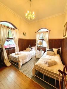 2 bedden in een slaapkamer met een kroonluchter bij Tyalgum Bed & Breakfast - Celestial Dew in Tyalgum
