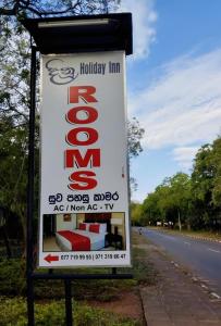 un panneau pour une auberge de vacances sur le côté d'une route dans l'établissement New Dinu Holiday Inn, à Kataragama