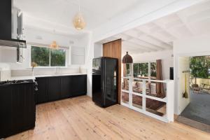 a kitchen with a black refrigerator in a room at Bungalow 127 at Avalon pde, 800m walk to beach in Avalon