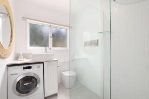 a bathroom with a washing machine and a shower at Bungalow 127 at Avalon pde, 800m walk to beach in Avalon