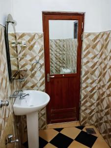 La salle de bains est pourvue d'un lavabo et d'un miroir. dans l'établissement New Dinu Holiday Inn, à Kataragama