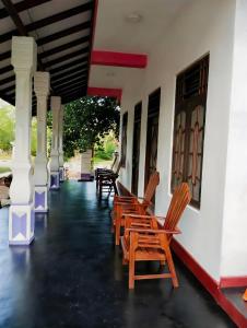 - une rangée de chaises assises sur la terrasse couverte d'une maison dans l'établissement New Dinu Holiday Inn, à Kataragama