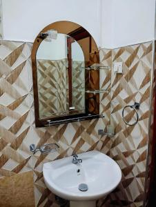 La salle de bains est pourvue d'un lavabo et d'un miroir. dans l'établissement New Dinu Holiday Inn, à Kataragama
