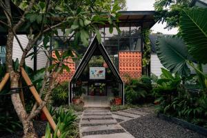 a house with a door in the middle of a garden at The Jungle Hostel Canggu in Canggu