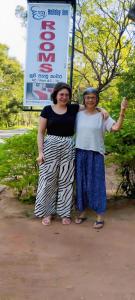 deux femmes debout l'une à côté de l'autre devant un panneau dans l'établissement New Dinu Holiday Inn, à Kataragama