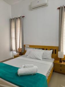 ein Schlafzimmer mit einem weißen Bett mit einer blauen Decke in der Unterkunft Ant Homes Kumbalangi by Afrind Hospitality in Kochi