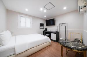 een witte slaapkamer met een bed en een tafel bij Gwanganli Calm Rest Hotel in Busan