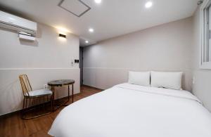a white bedroom with a bed and a chair at Gwanganli Calm Rest Hotel in Busan