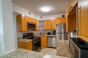 una cocina con armarios de madera y electrodomésticos de acero inoxidable en Two Bedroom on the Beach with balcony and Oceanview, en Miami Beach