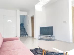 un soggiorno con divano rosa e TV di White Mountain Pool Villas a Paphos