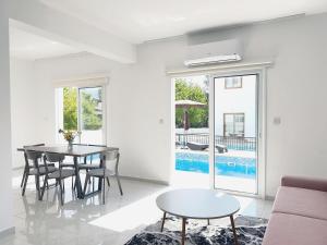 un soggiorno con tavolo, sedie e piscina di White Mountain Pool Villas a Paphos