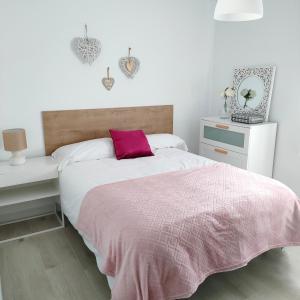 um quarto com uma cama com um cobertor rosa em Villa Memé Playa em Málaga
