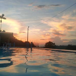 a pool of water with a sunset in the background at Quinta Felicidad in Pedro Vicente Maldonado