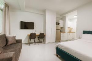 a bedroom with a bed and a couch and a kitchen at Snug studio apartment with pvt garden access III in Athens