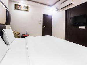 1 dormitorio con cama blanca y puerta negra en OYO Hotel Br Villa, en Nārnaul