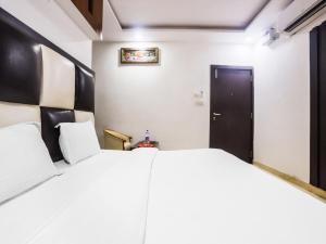 a bedroom with a large white bed and a black door at OYO Hotel Br Villa in Nārnaul