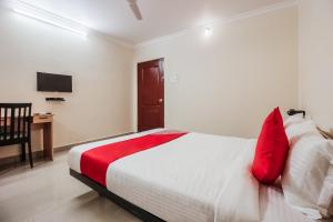 Schlafzimmer mit einem Bett mit roten Kissen und einem Schreibtisch in der Unterkunft Flagship Neknampur Near Golconda Fort in Haidar Sāhibgūda